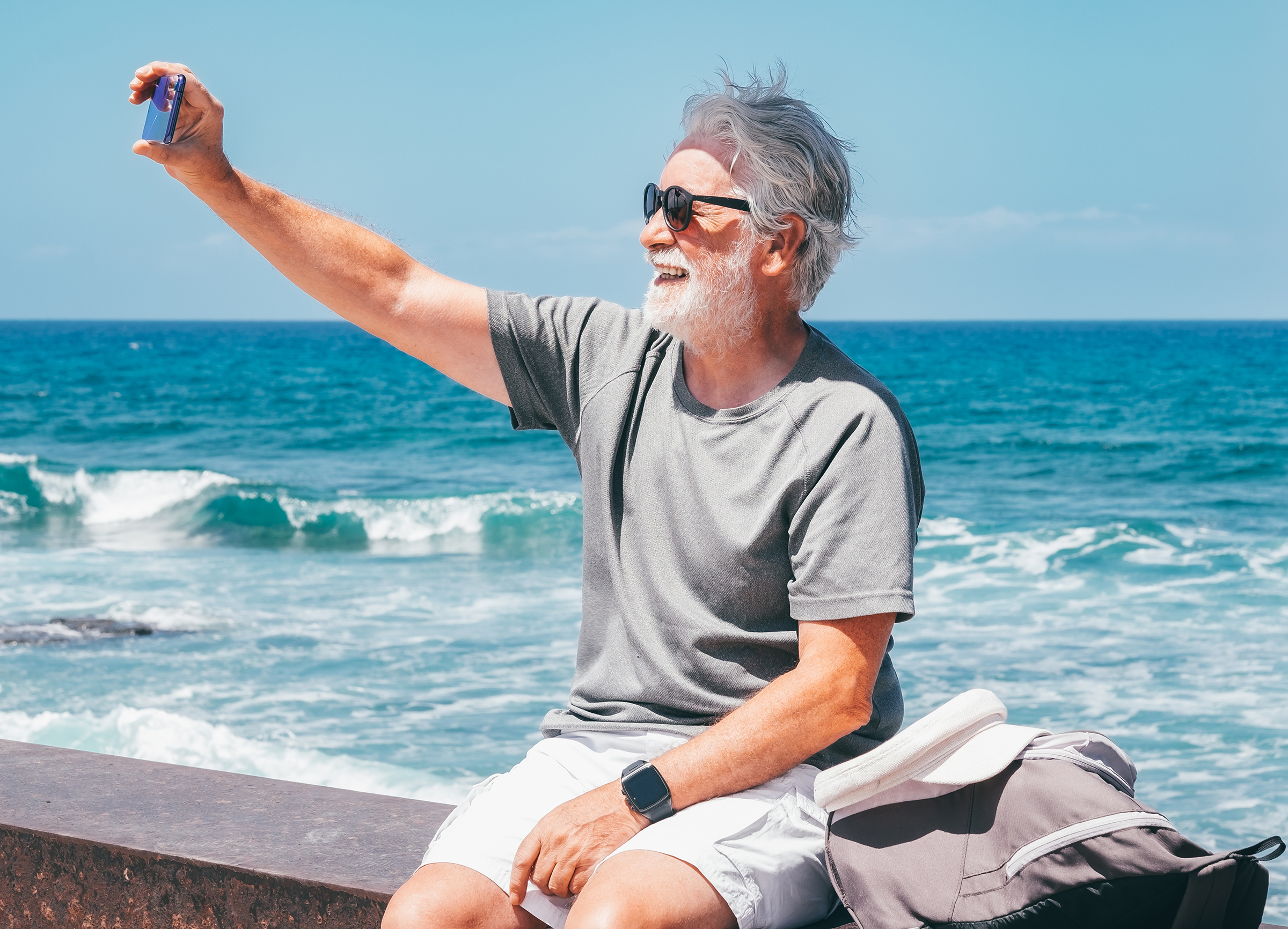 Cheerful Senior Bearded Caucasian Man Sitting Close the Beach at